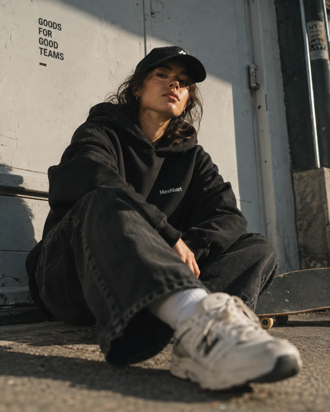 Person i sort hoodie med logo, siddende udendørs
