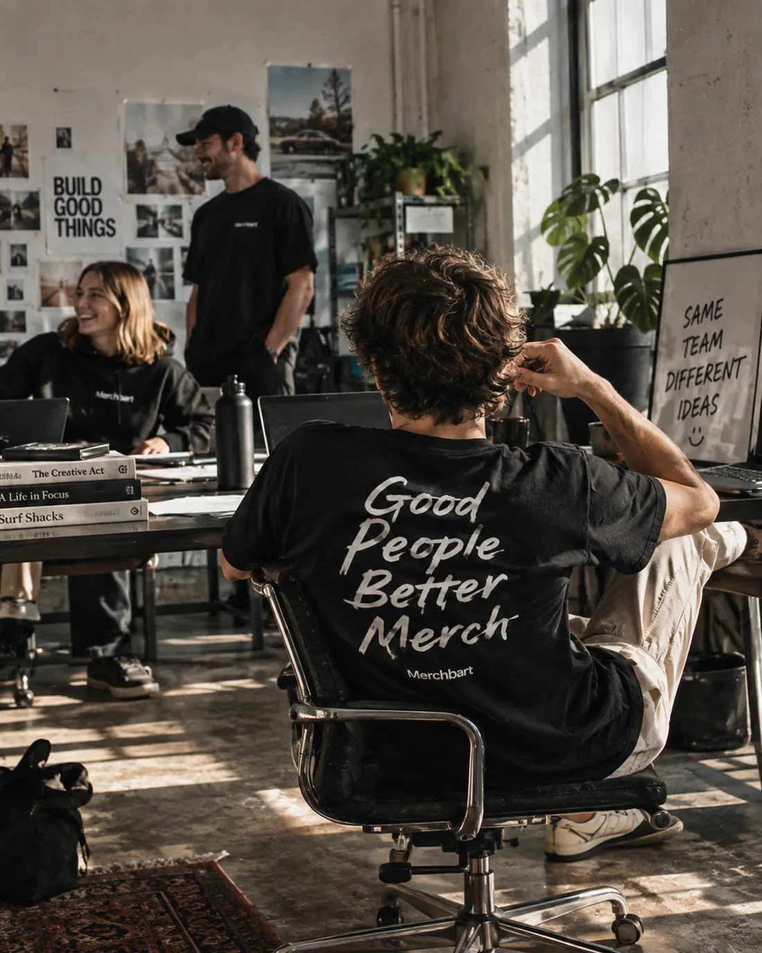 Kontor med fire kolleger i Merchbart-tøj. Forrest en sort t-shirt med tryk på ryggen.